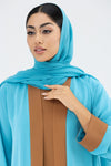 Woman wearing a blue abaya with a brown panel