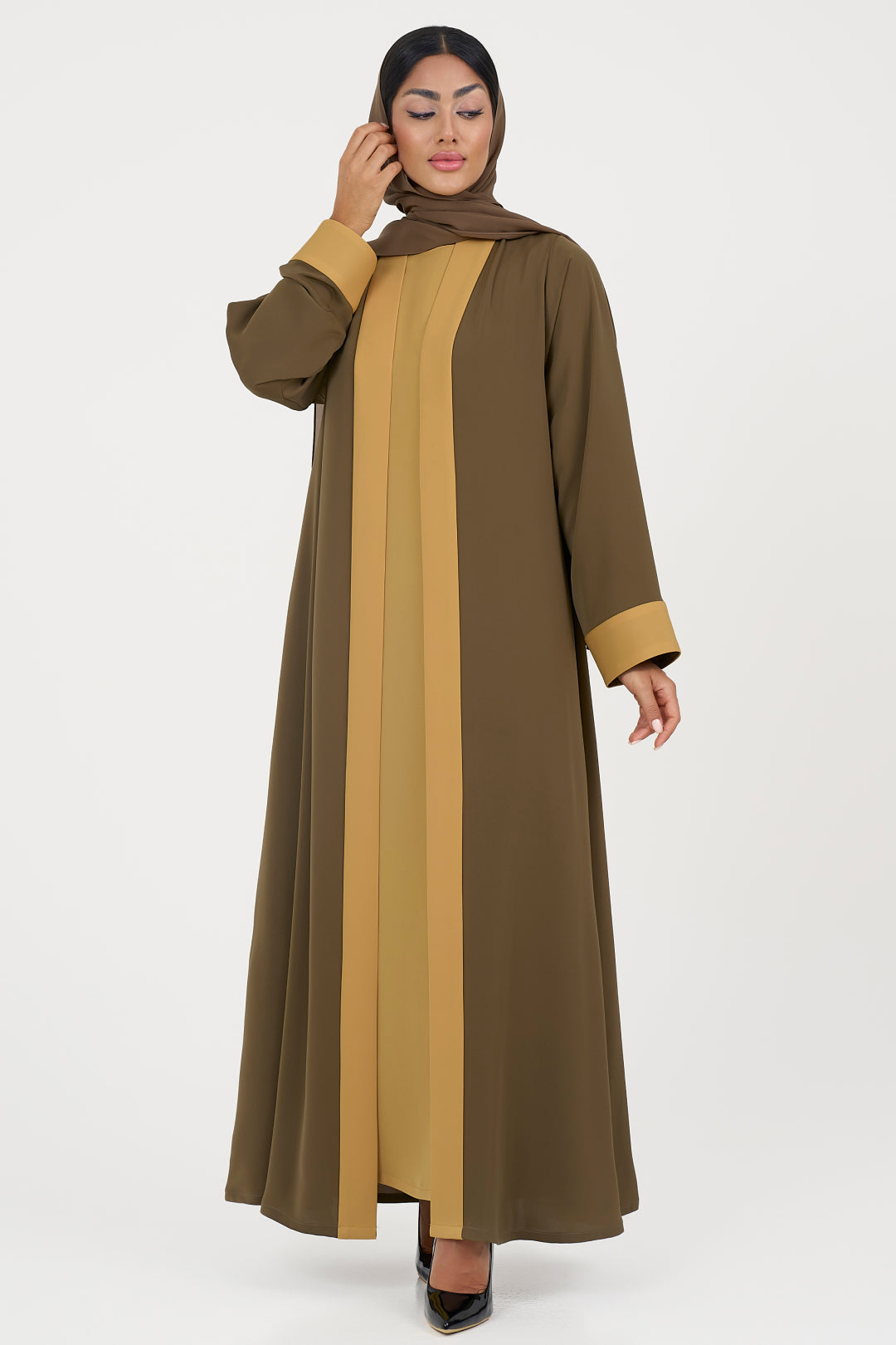 Woman wearing olive and yellow abaya on a white background