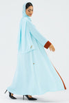 Woman wearing a light blue hijab and dress with brown accents