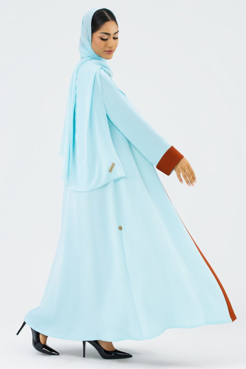 Woman wearing a light blue hijab and dress with brown accents