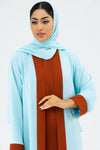 Woman wearing a light blue hijab and brown dress