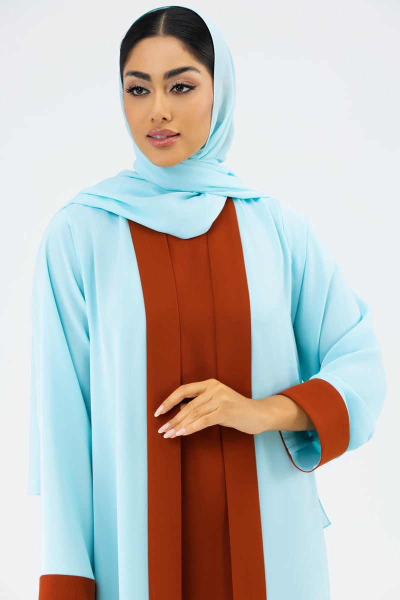 Woman wearing a light blue hijab and brown dress