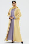 Woman wearing a yellow abaya with a purple dress