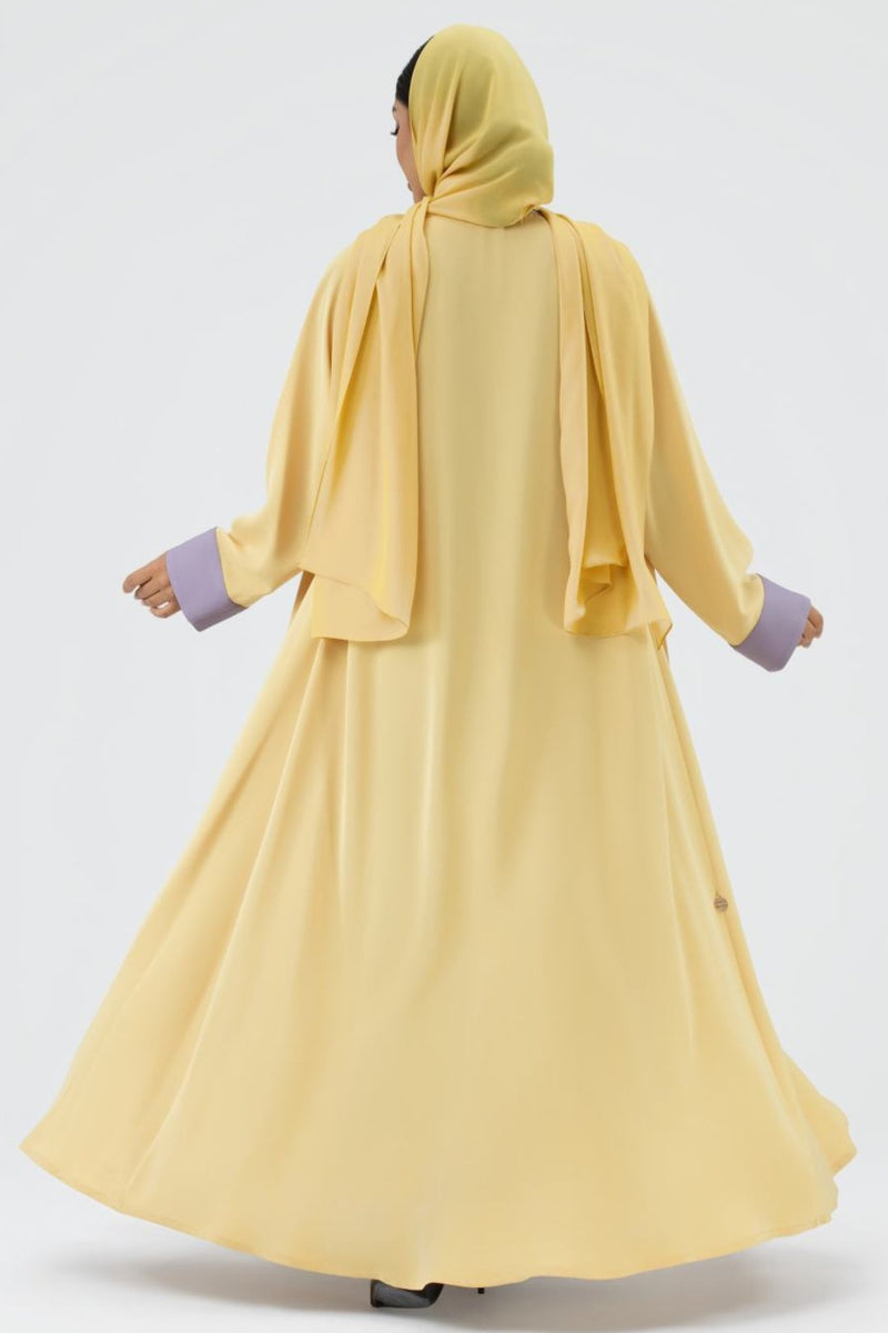 Yellow abaya with purple cuffs on a white background