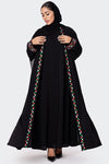 Woman wearing a black abaya with colorful embroidery on a white background