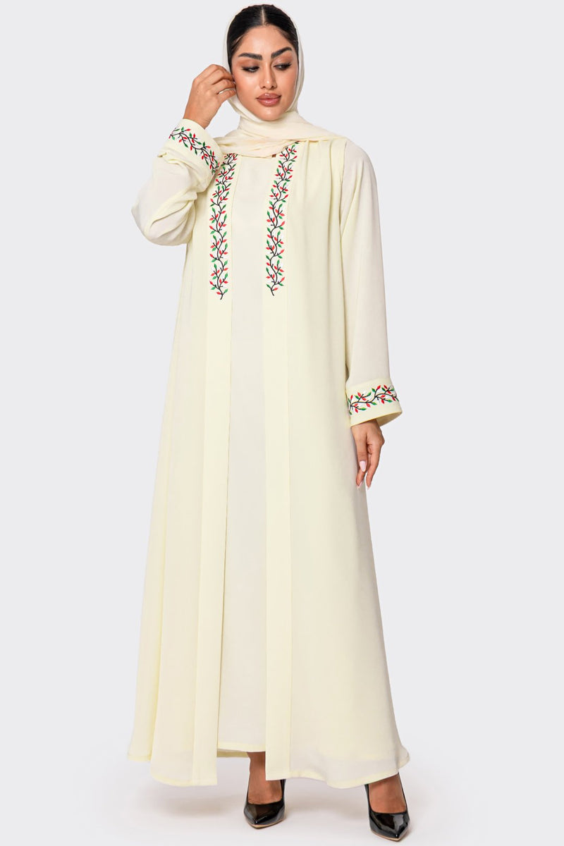 Woman wearing a cream-colored abaya with floral embroidery on a white background