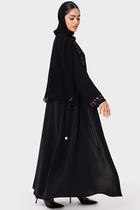 Woman wearing a black abaya with colorful embroidery on a white background