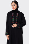 Woman wearing a black abaya with colorful embroidery on a white background