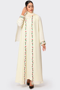 Woman wearing a cream-colored abaya with floral embroidery on a white background