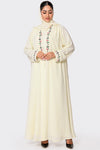 Woman wearing a cream-colored abaya with floral embroidery on a white background
