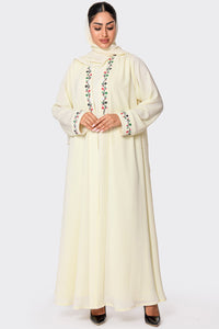 Woman wearing a cream-colored abaya with floral embroidery on a white background