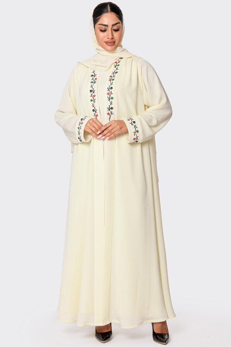 Woman wearing a cream-colored abaya with floral embroidery on a white background