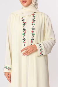 Cream-colored abaya with floral embroidery on a plain background