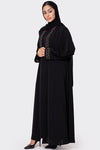 Woman wearing a black abaya with colorful embroidery on a white background