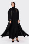Woman wearing a black abaya with embroidered details on a white background