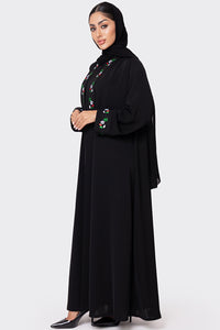 Woman wearing a black abaya with floral embroidery on a white background