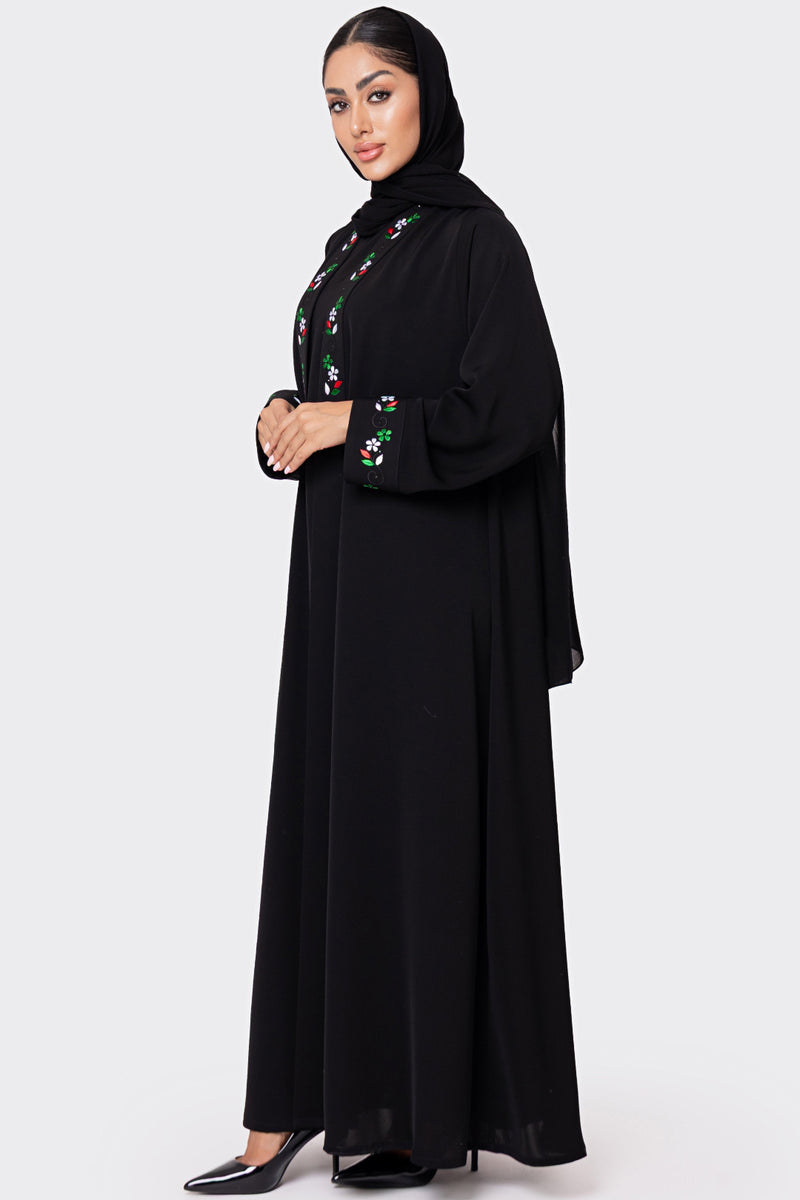 Woman wearing a black abaya with floral embroidery on a white background