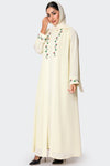 Woman wearing a cream-colored abaya with floral embroidery on a white background