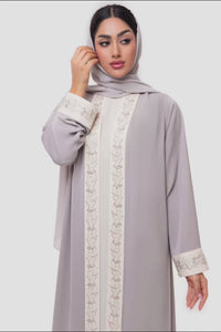 Woman wearing Nivana Abaya in light Beige and off white embroidery, standing straight front view in an elegant fashion look