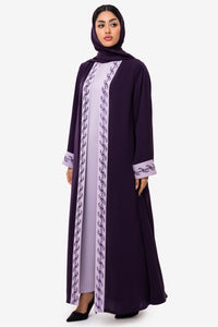 Woman wearing elegant light and dark purple embroidered Fouz Abaya, standing left side pose