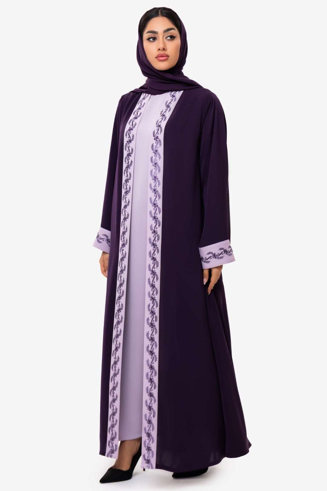 Woman wearing elegant light and dark purple embroidered Fouz Abaya, standing left side pose