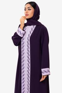Elegant woman in embroidered light and dark purple Fouz Abaya with Austrian crystal detailing, front standing pose.