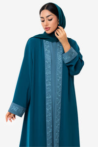 front view of the Mitra Abaya in teal on a woman