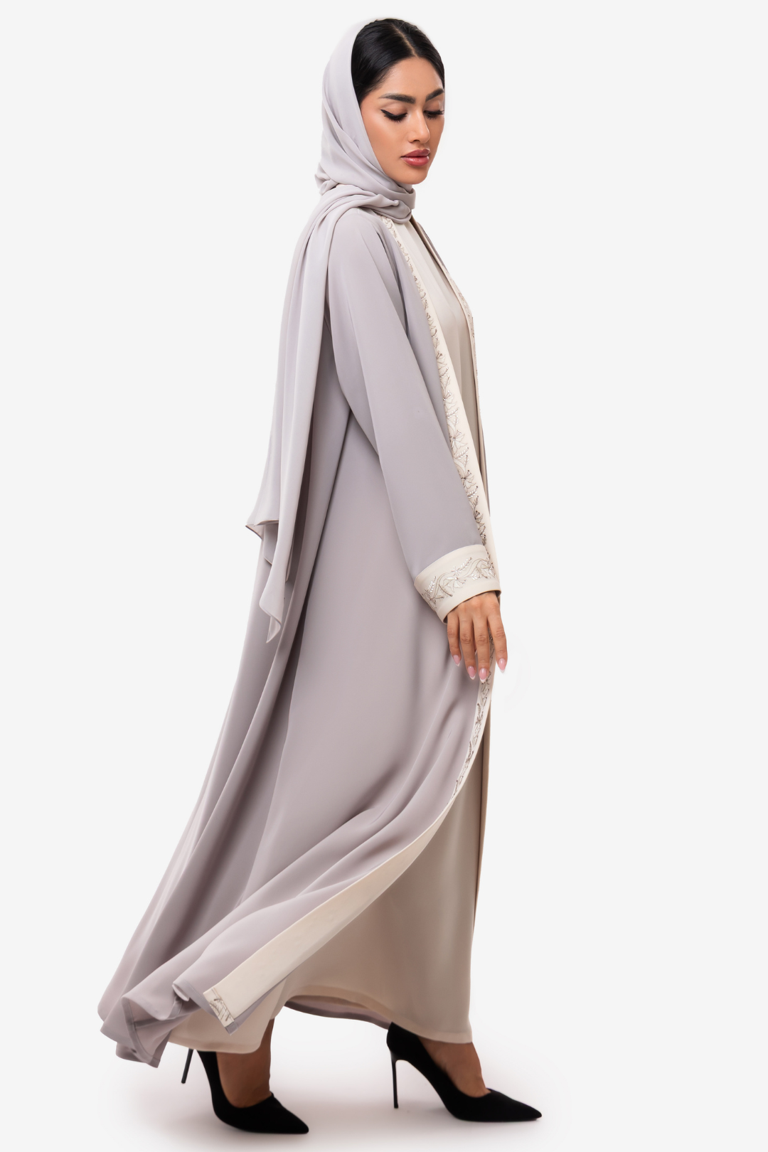 Woman wearing embroidered light beige and off white Nivana Abaya, standing right side elegant pose