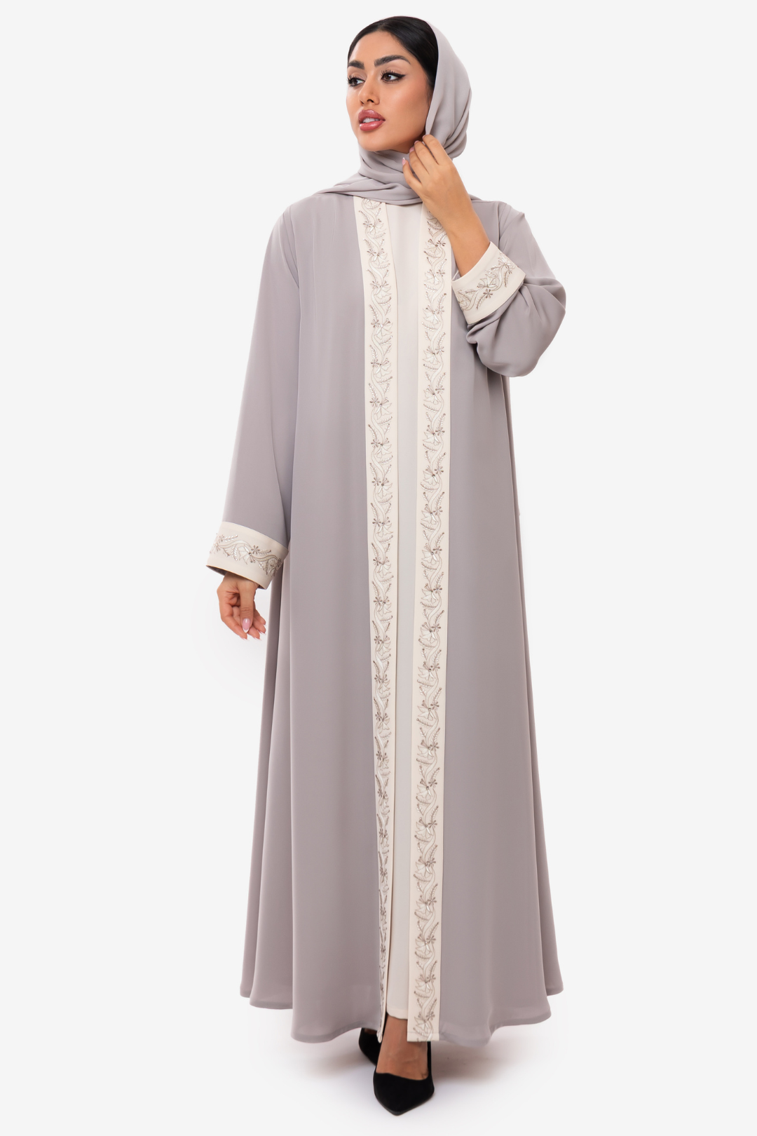 Woman wearing Nivana Abaya in light Beige and off white embroidery, standing straight in an elegant fashion look