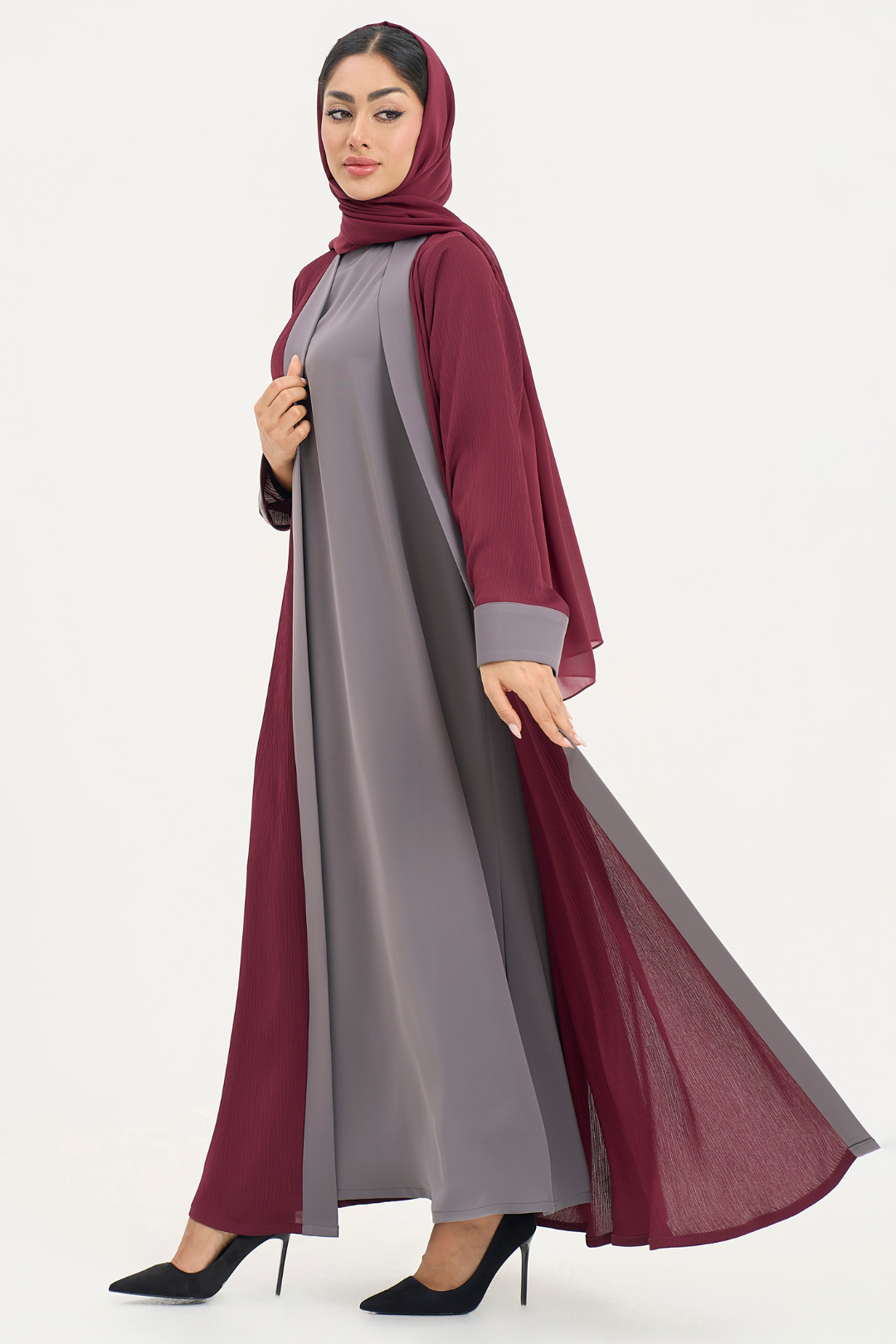 Woman in Noor Abaya, burgundy and grey elegant abaya, standing left showcasing soft drape and silhouette.