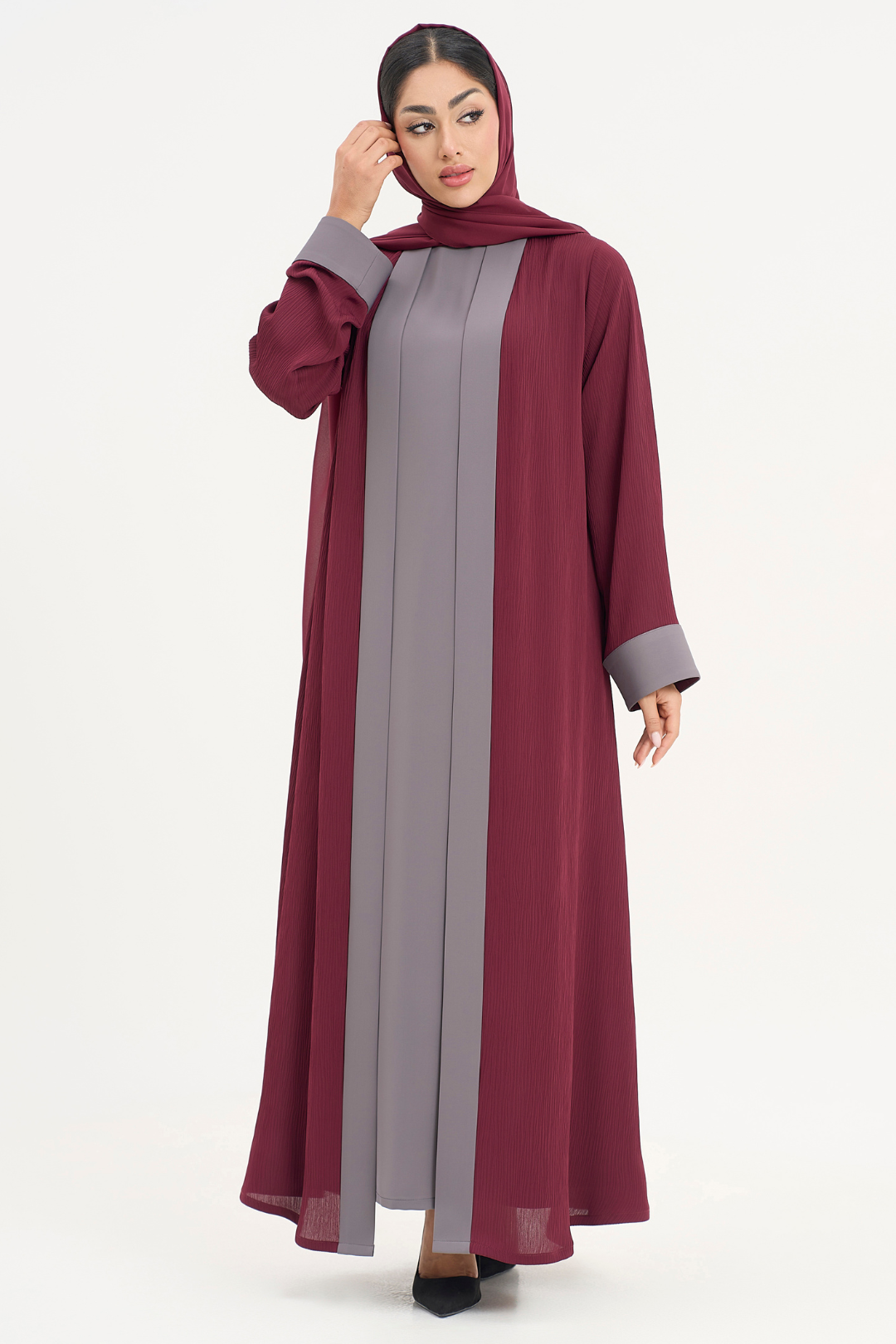 Woman in Noor Abaya, two-toned burgundy and grey elegant abaya, standing straight with a minimal and sophisticated look.