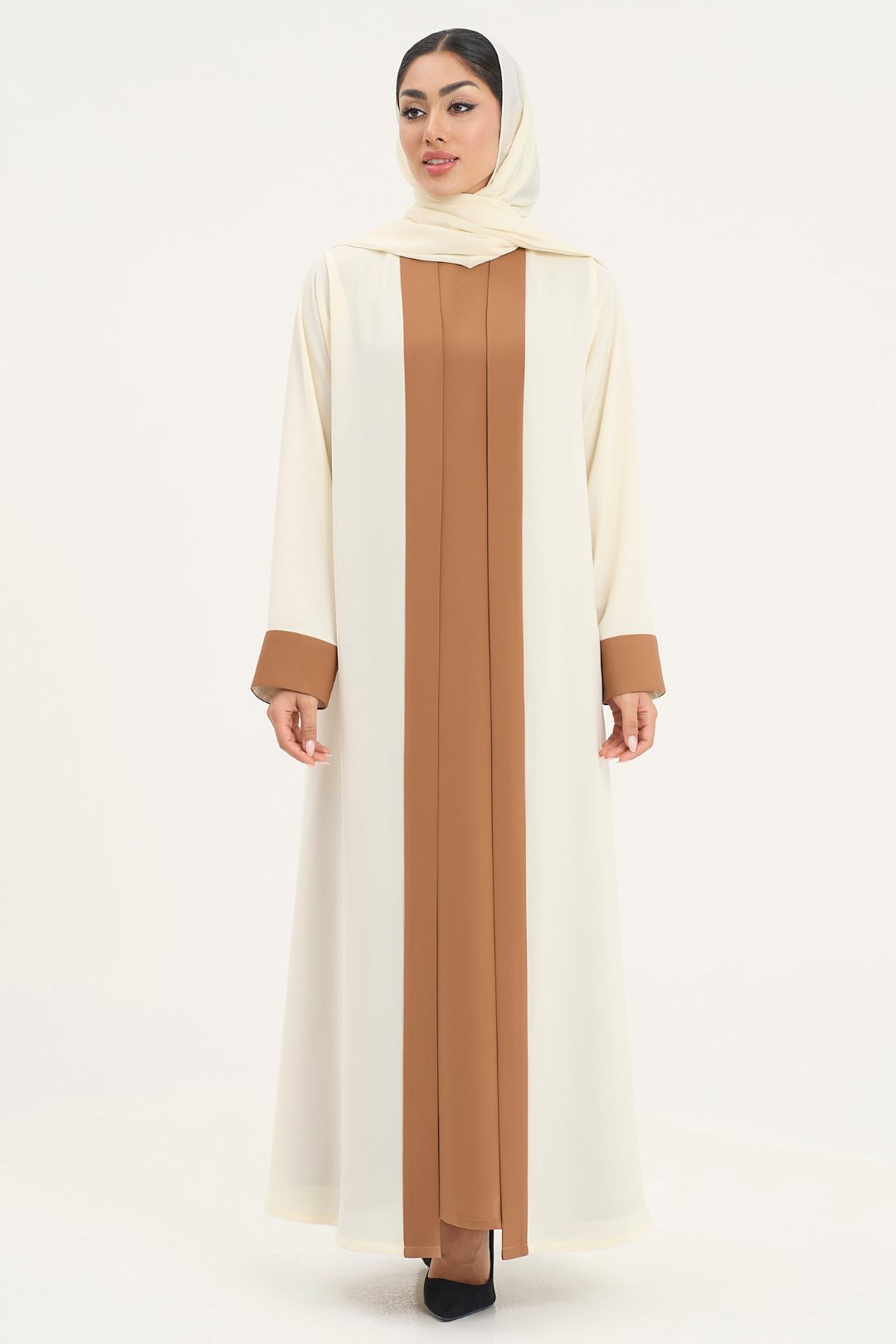 Rana Abaya in a two-toned off-white and camel color, standing straight in an elegant pose