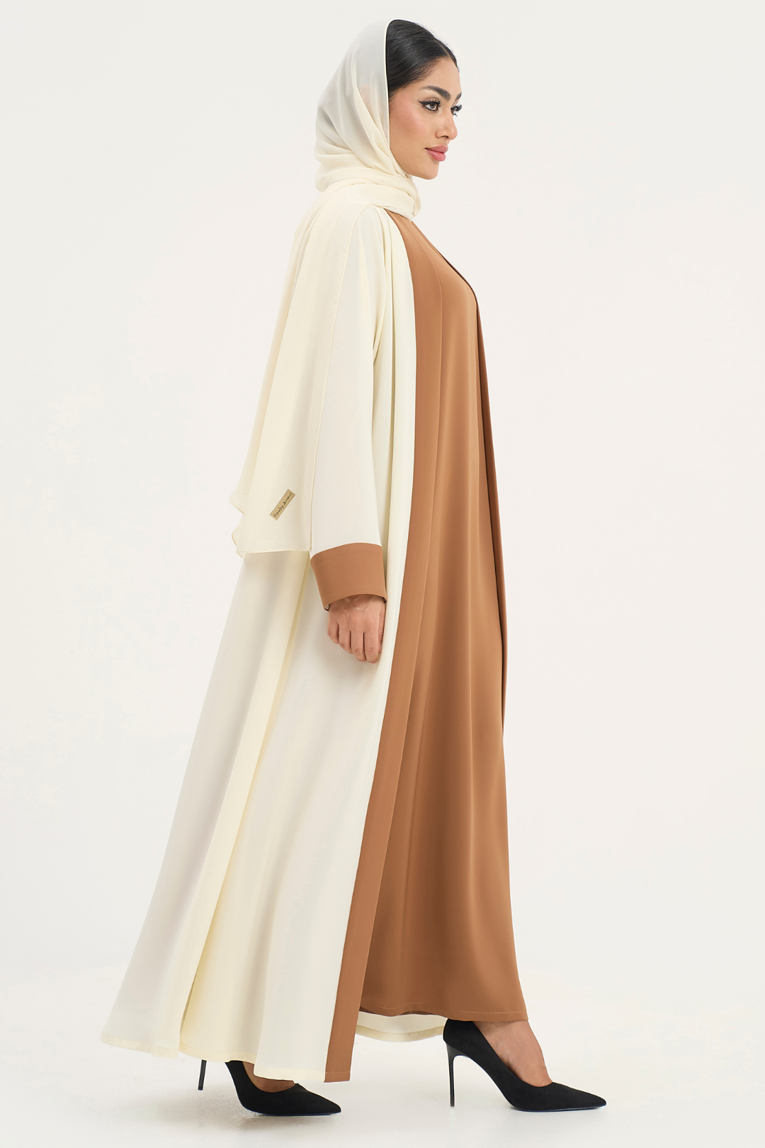 Rana Abaya in a two-toned off-white and camel color, standing right in an elegant pose
